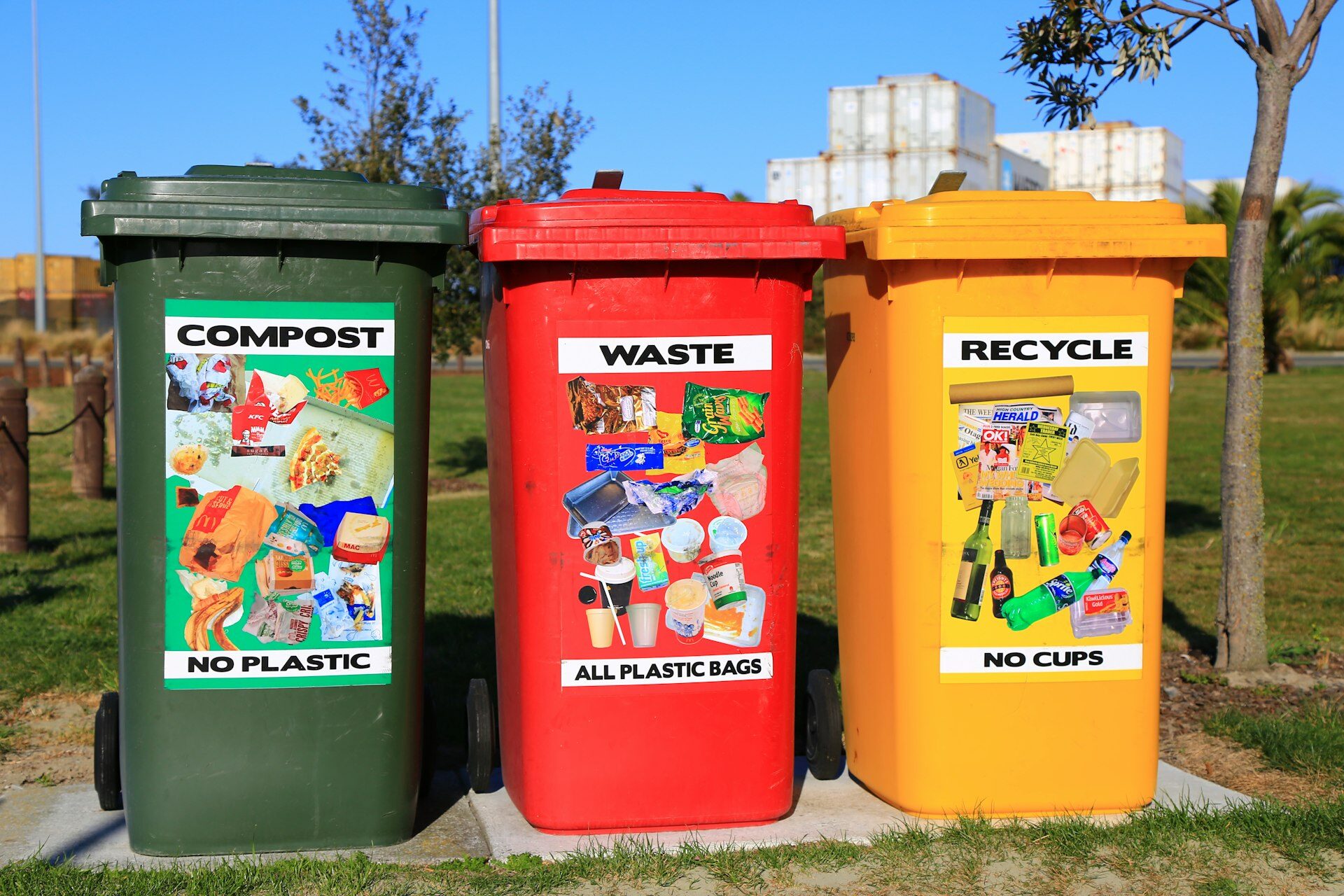 Three colour-coded waste bins for compost, general waste, and recycling